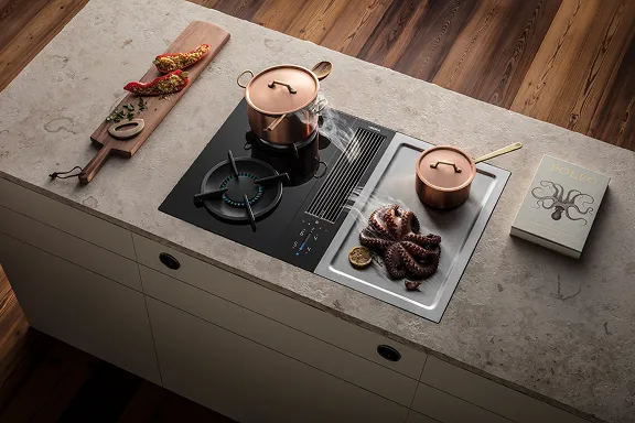 Aufsicht auf BORA Kochfeld mit Gasbrenner und Tepan-Grillfläche in heller Insel. Ein Oktopus dämpft auf der Tepan-Fläche. Kochbuch "POLPO" liegt daneben.